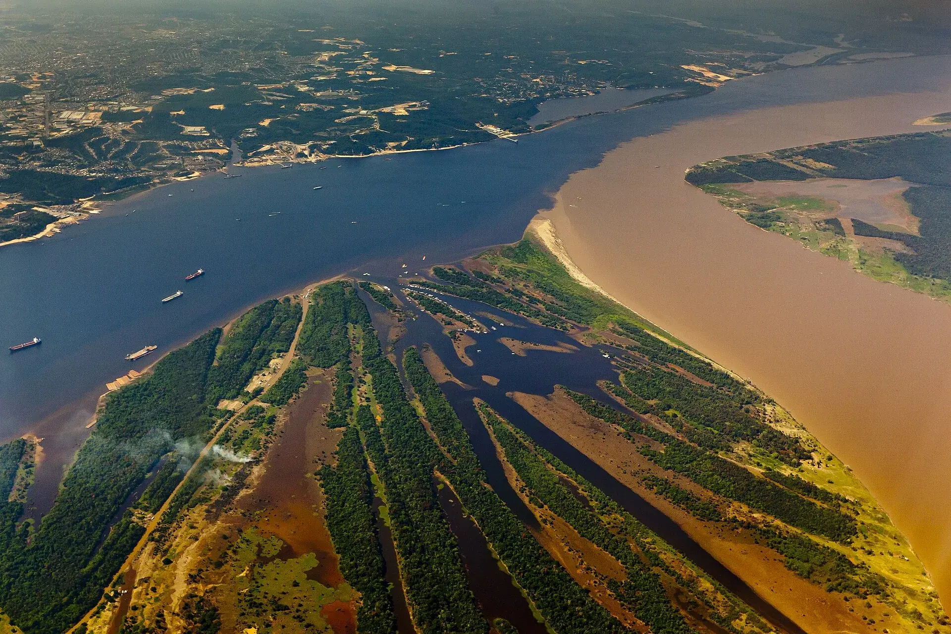Vista aérea do encontro das águas do Rio Negro com o Solimões, próximo a Manaus, com embarcações navegando
